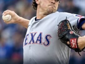 Cal Quantrill of the Texas Rangers pitching during the game against the Seattle Mariners, wearing a gray Rangers uniform and blue cap.